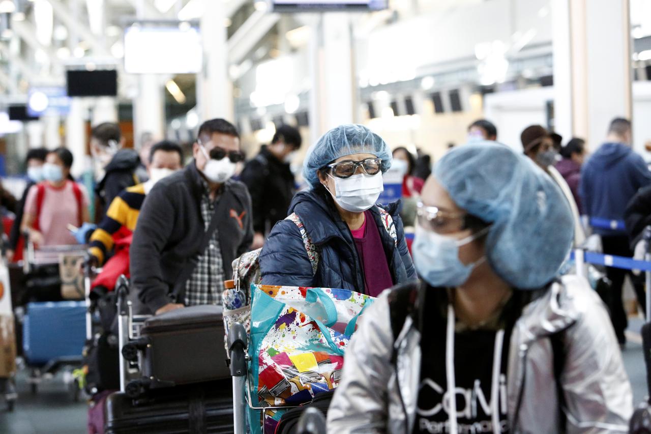 People wearing face masks and goggles wait to check in for an international flight at the Vancouver International Airport in Richmond, British Columbia, Canada March 16, 2020. REUTERS/Jesse Winter